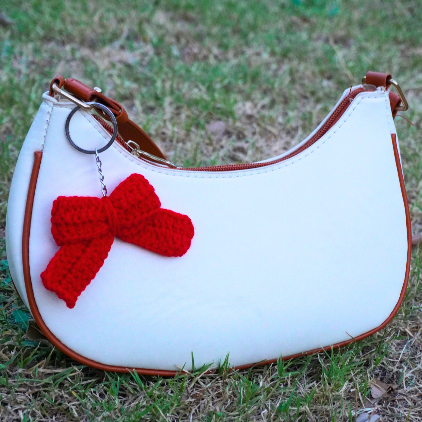 White handbag with a red bow on grass