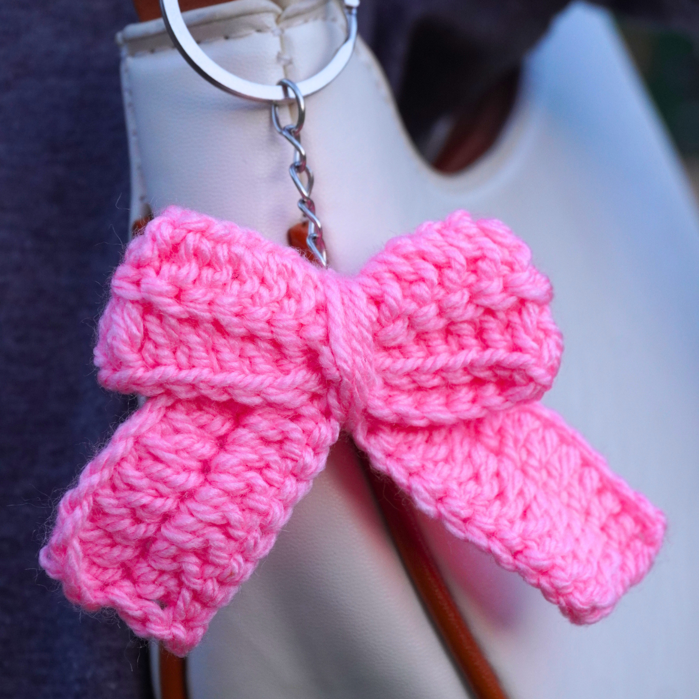 Pink knitted bow keychain on a mannequin hand