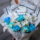 Bouquet of blue and white flowers with a 'Get Well Soon' card on a tiled floor.